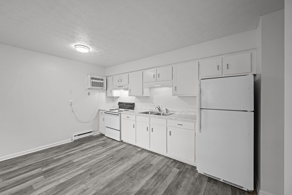 A kitchen with white cabinets and a refrigerator.