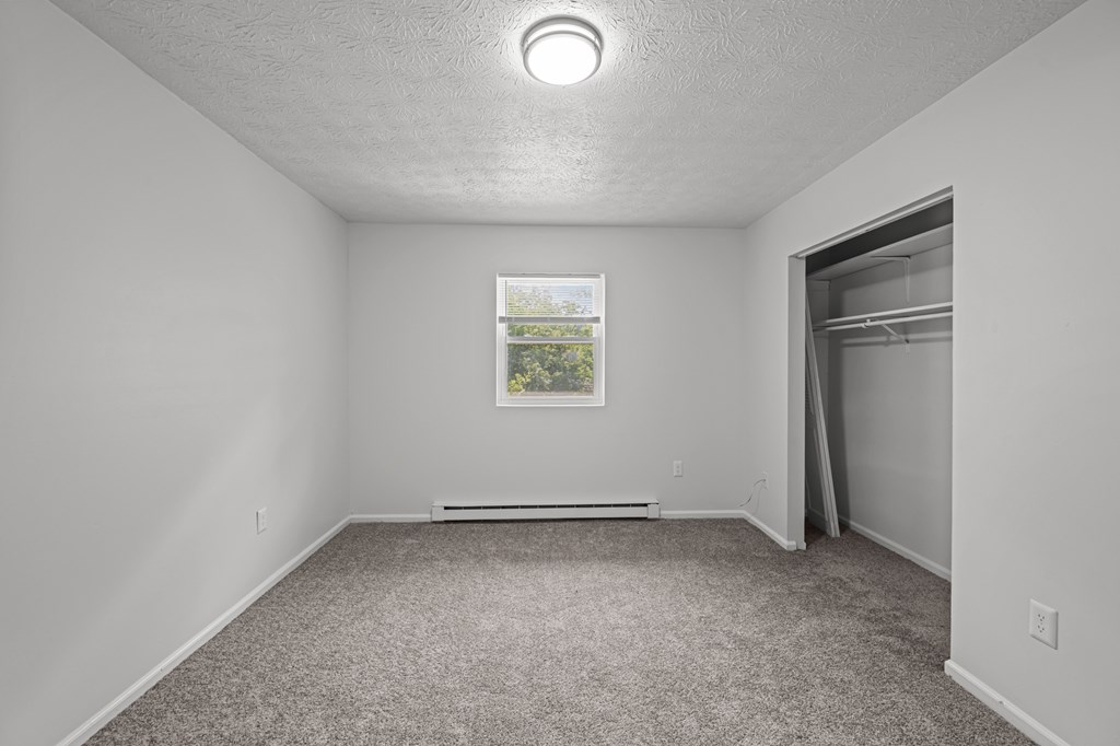 A room with a window and a picture on the wall.