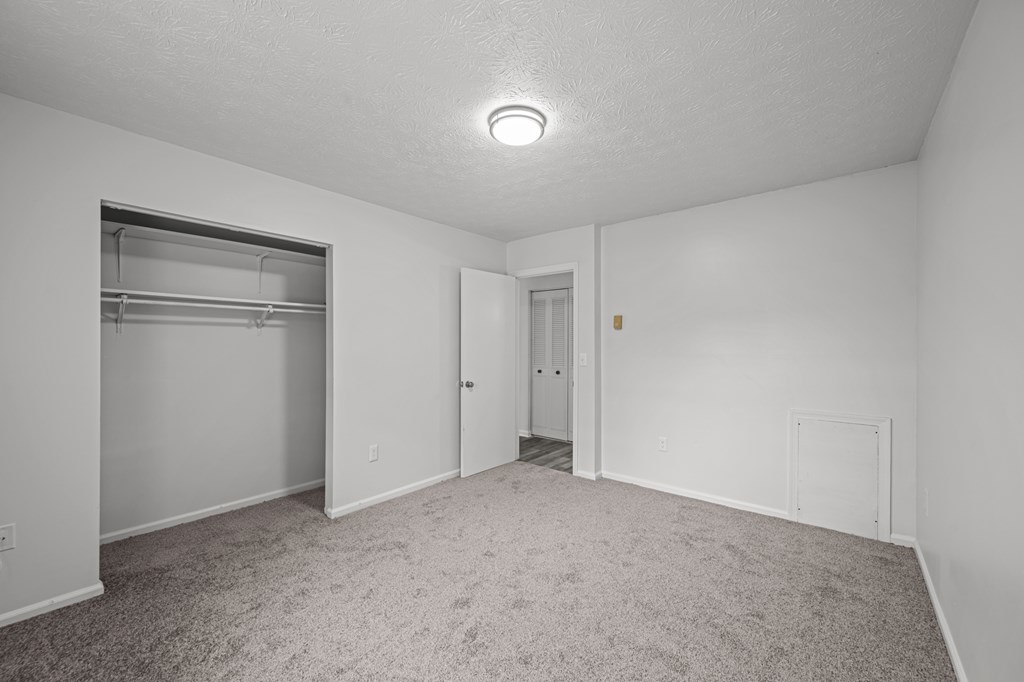A sparsely furnished room with a closet and a door.