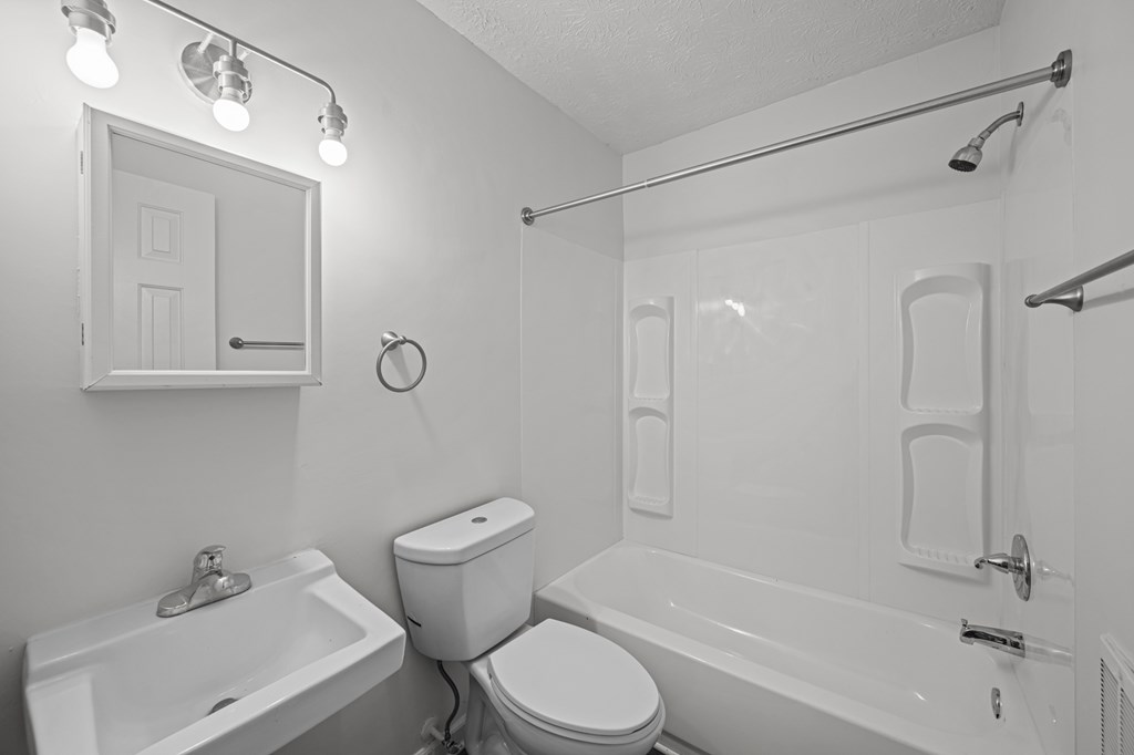 A white bathroom with a toilet, sink, and bathtub.