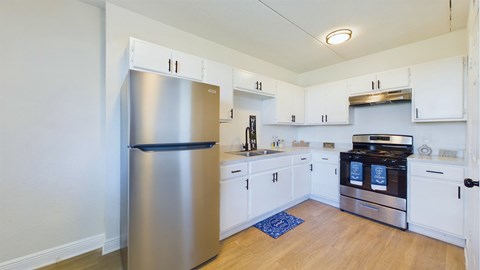 A kitchen with a stainless steel refrigerator and white cabinets.