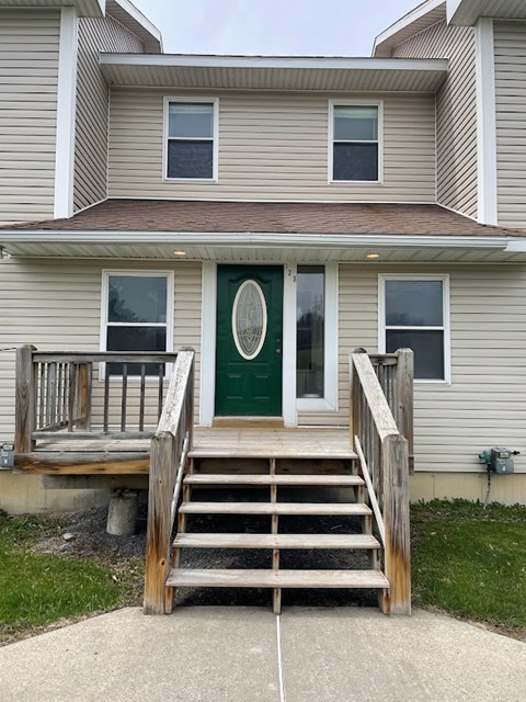 A house with a green door and a wooden staircase leading to it.