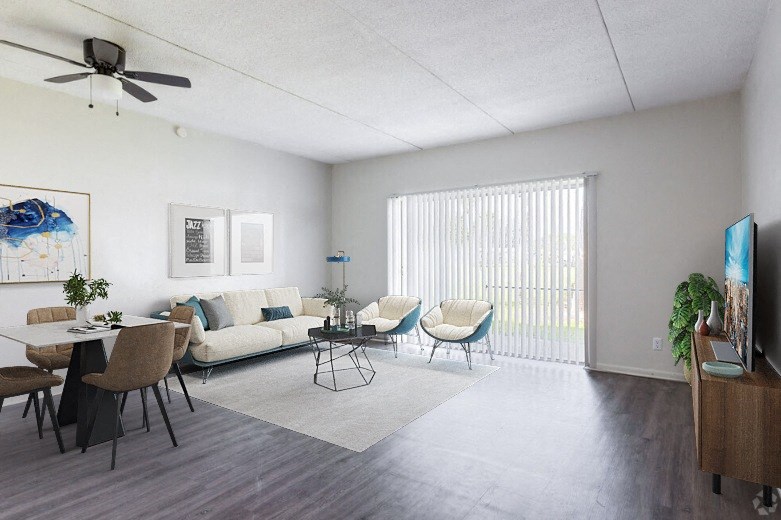 A living room with a white couch, a dining table with chairs, and a television on a wooden stand.