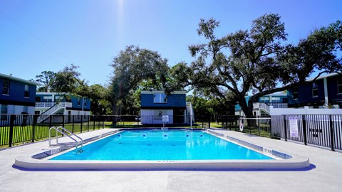 A swimming pool surrounded by trees and buildings.