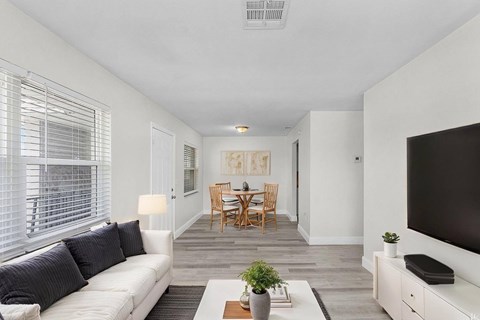 A living room with a white couch, a wooden table, and a television.