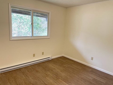A room with a window and wooden flooring.