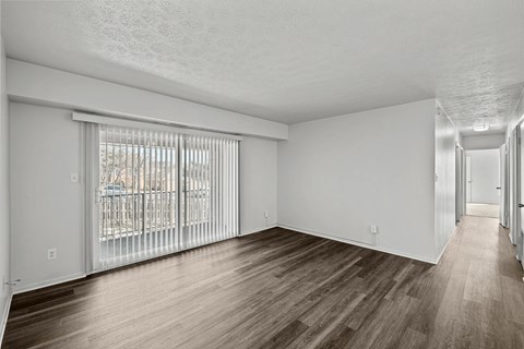 A spacious room with wooden flooring and white walls.