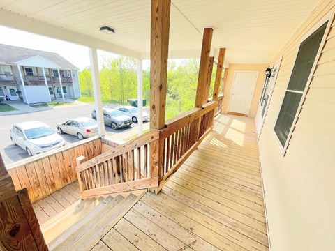 A balcony with a railing and a view of a parking lot and trees.