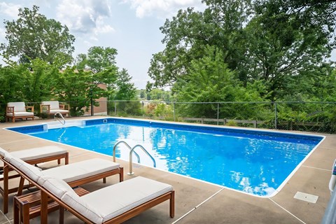 A pool with a blue tinted water and a white sunbed.