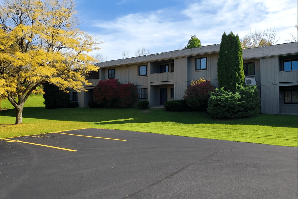 A parking lot in front of a building with trees and bushes.