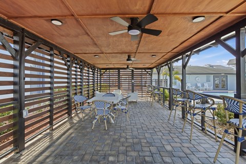 A patio with a table and chairs and a ceiling fan.