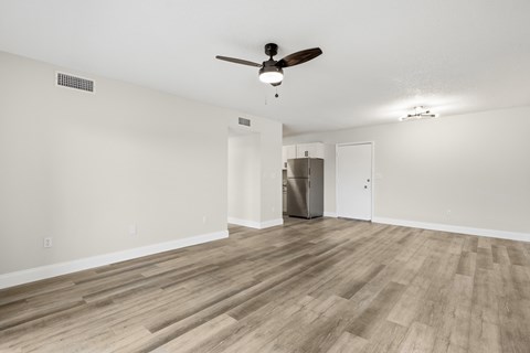 A room with a ceiling fan and a refrigerator in the corner.