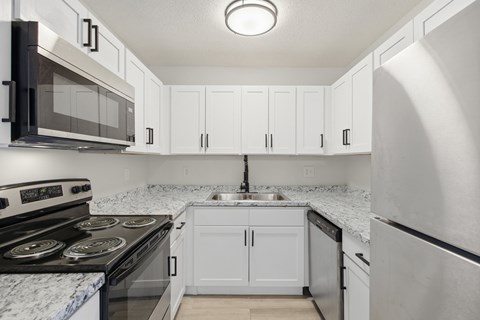 A kitchen with white cabinets and a marble countertop.