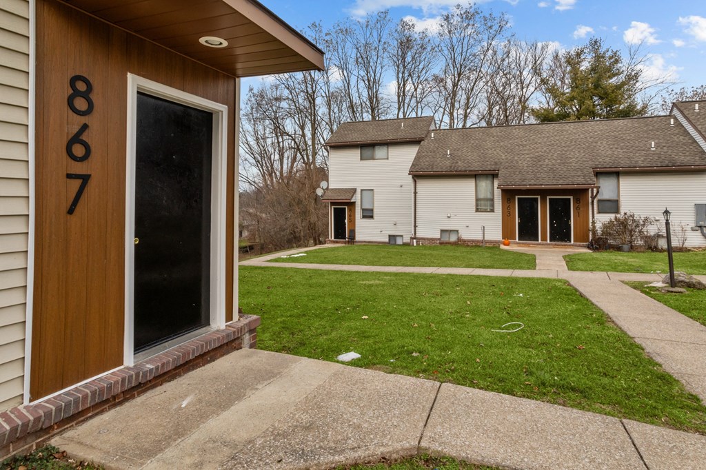 A house numbered 8867 with a brown door and a small front yard.