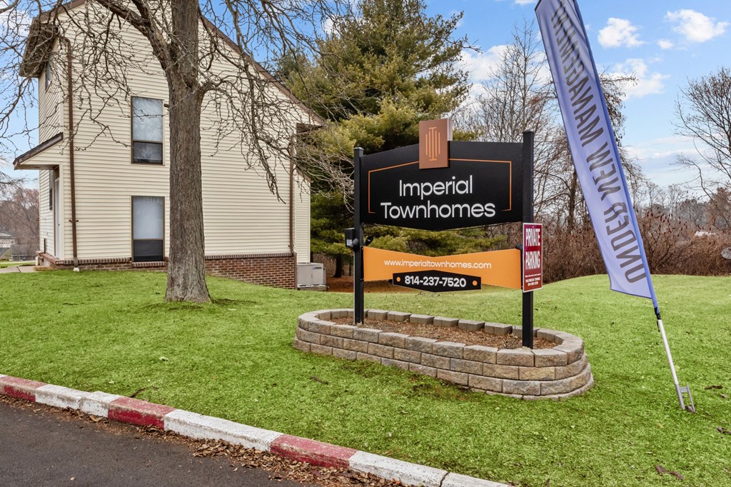 A sign for Imperial Townhomes stands in front of a house.