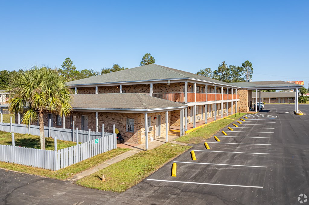 A parking lot in front of a building with a palm tree.