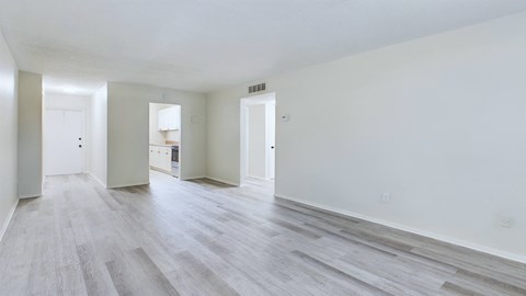 A spacious room with wood flooring and white walls.
