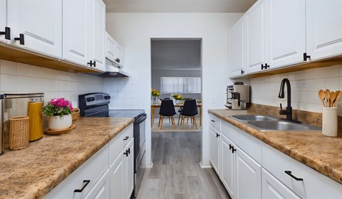 A kitchen with white cabinets and a brown countertop.