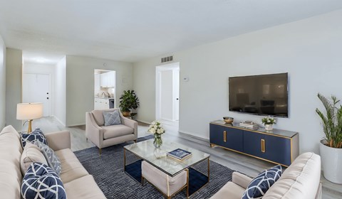 A living room with a white couch, a coffee table, and a TV on a cabinet.