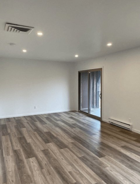 a living room with white walls and a sliding glass door
