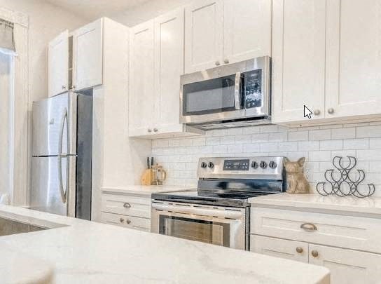 a kitchen with white cabinets and a stove and a microwave