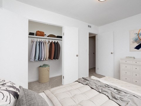 a bedroom with a closet and a bed and a closet with clothes hanging on it