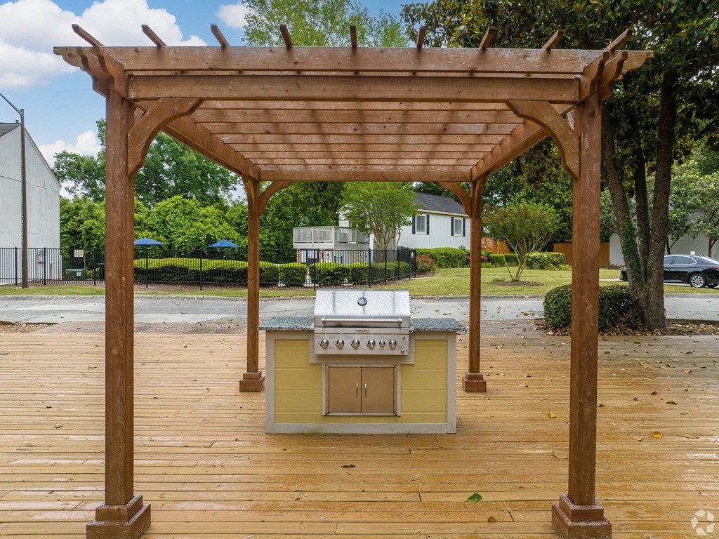 a barbecue grill is under a wooden deck with a pergola