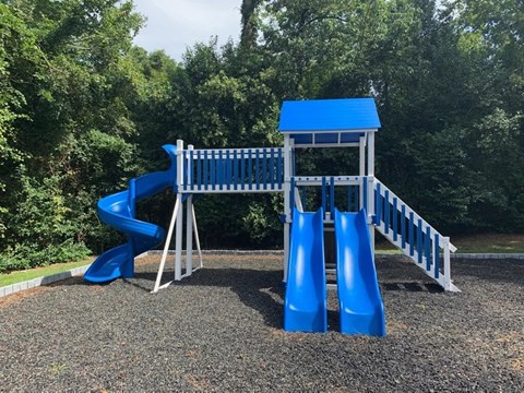 a playground with a blue slide and a swing set