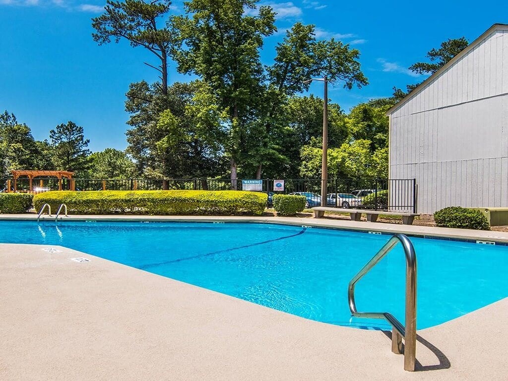 a swimming pool with a building and trees in the background