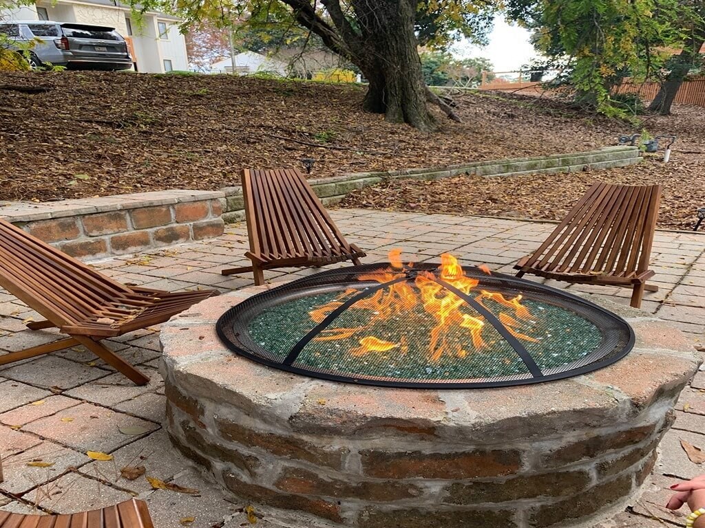 a fire pit with two wooden chairs around it