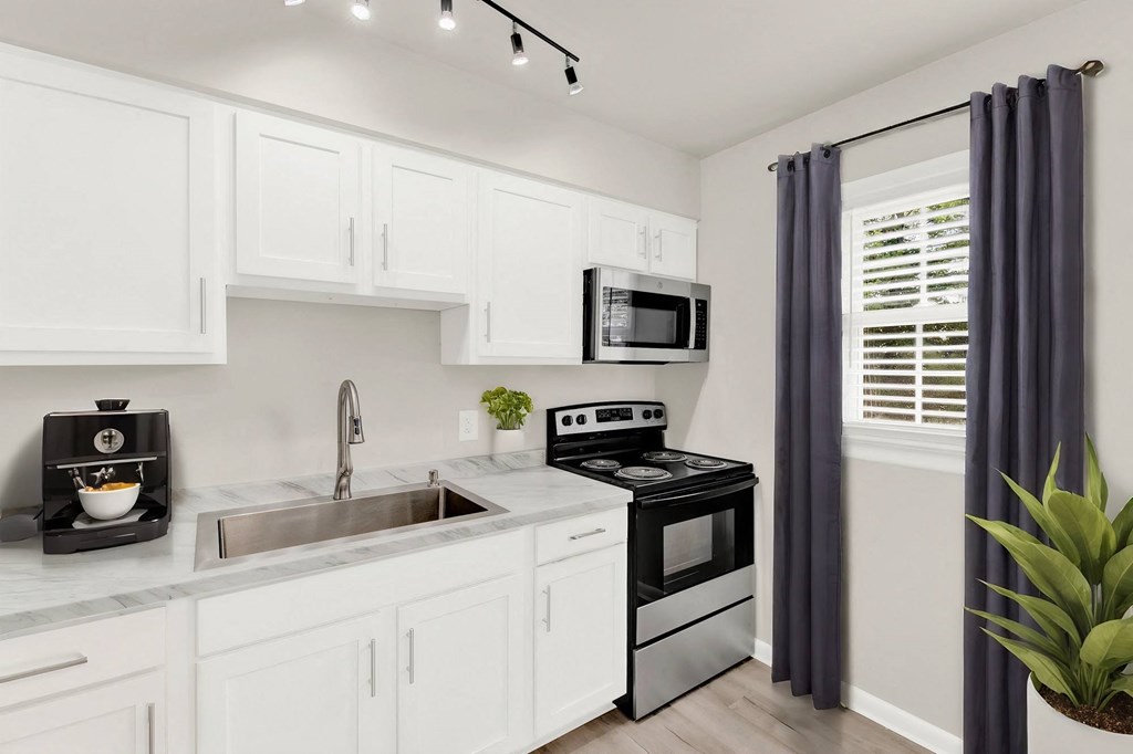 a kitchen with white cabinets and black appliances and a window