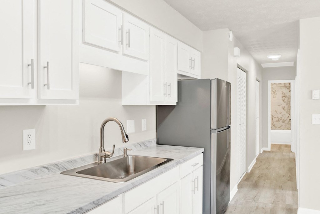 a white kitchen with a stainless steel refrigerator and sink