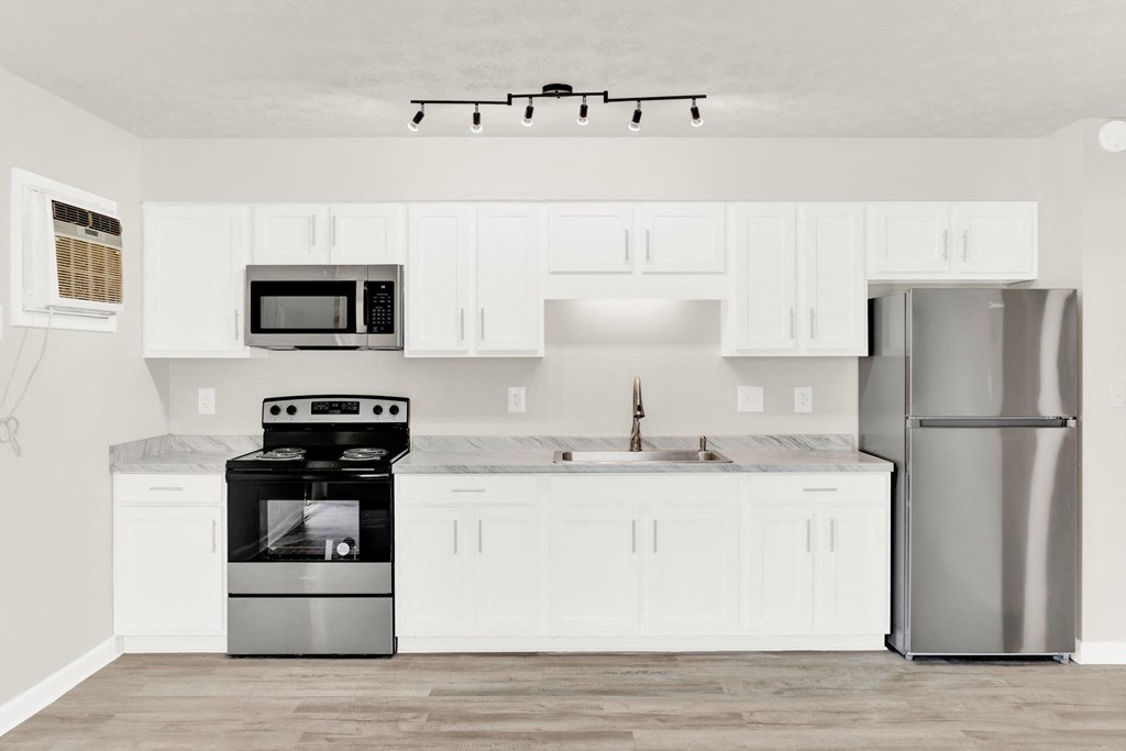a white kitchen with stainless steel appliances and white cabinets