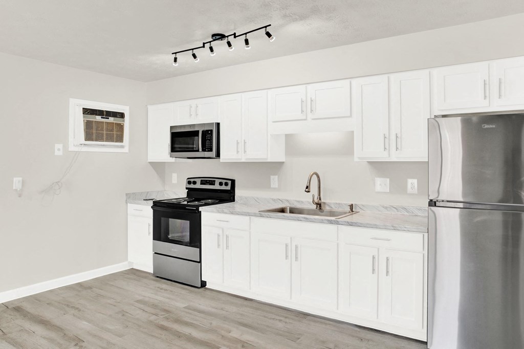 a white kitchen with stainless steel appliances and white cabinets
