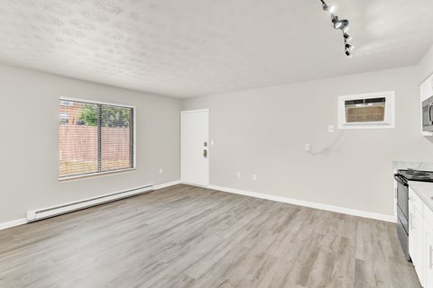 the living room of an apartment with wood flooring and a window