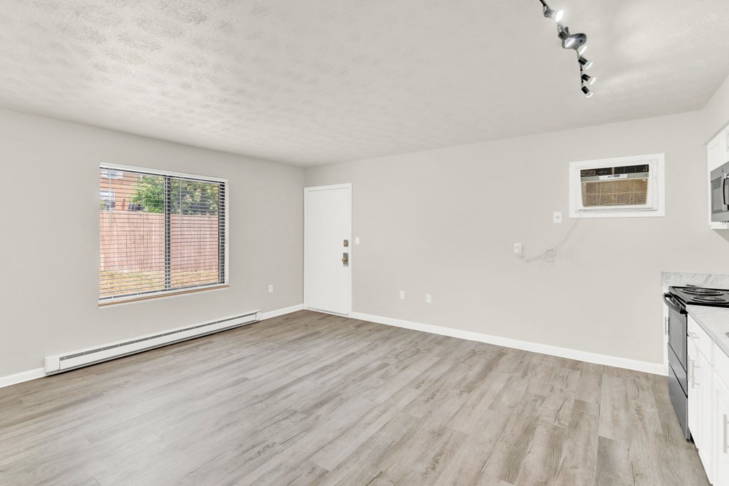 the living room of an apartment with wood flooring and a window