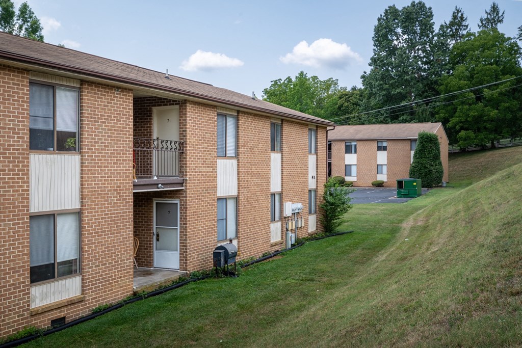 a row of brick apartment buildings on a hill with a grass field