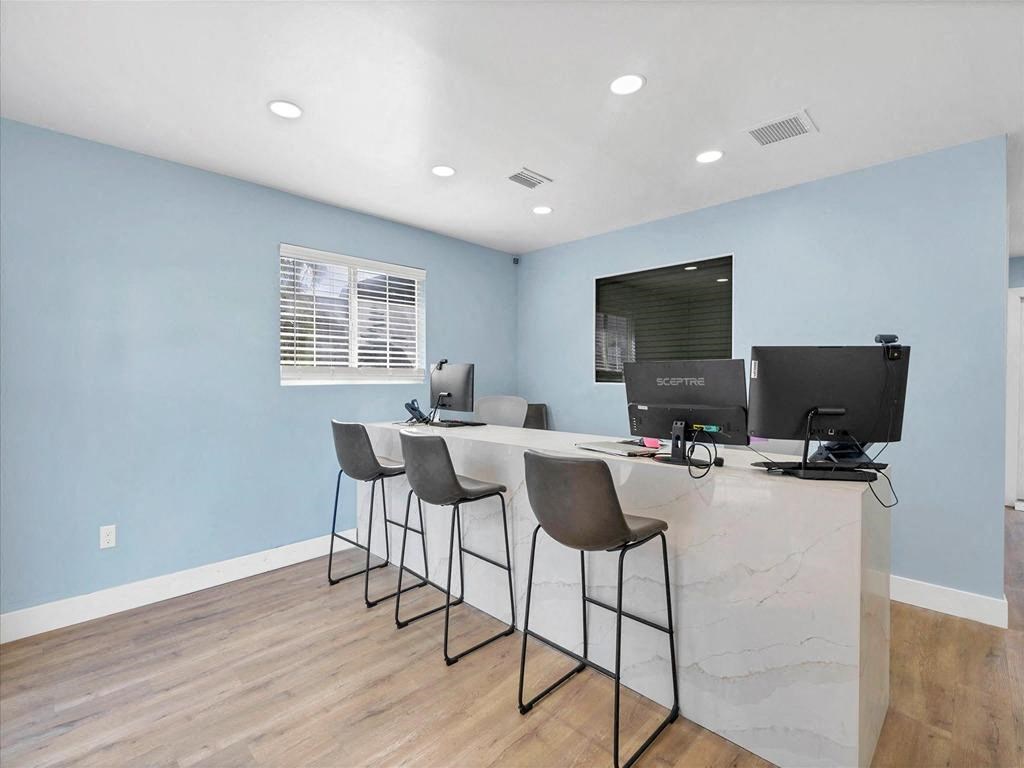 a room with a long desk with three computers on it