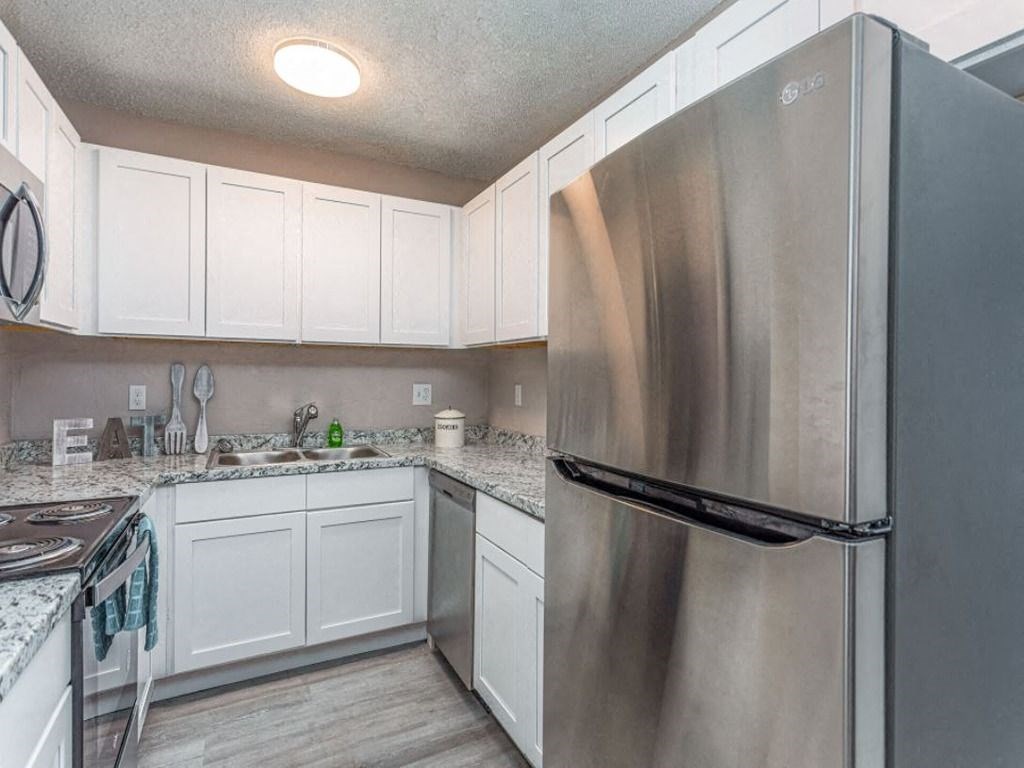 a kitchen with white cabinets and a stainless steel refrigerator
