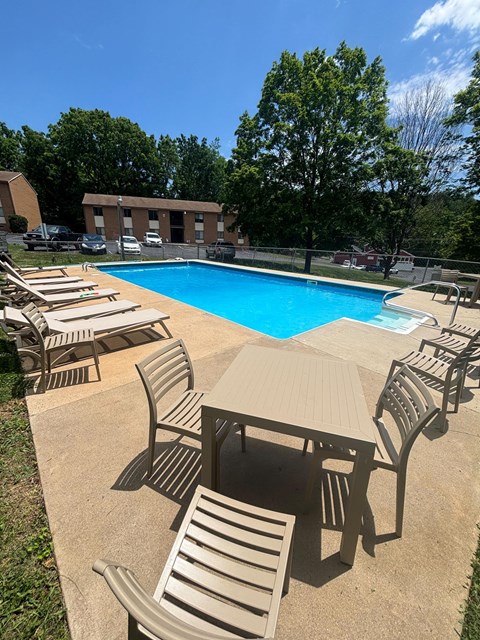 A pool surrounded by chairs and tables.