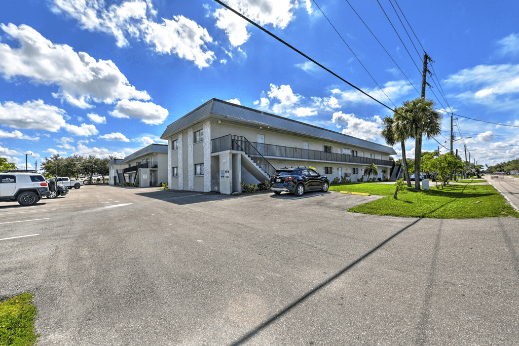 A sunny day at a parking lot with a white building in the background.