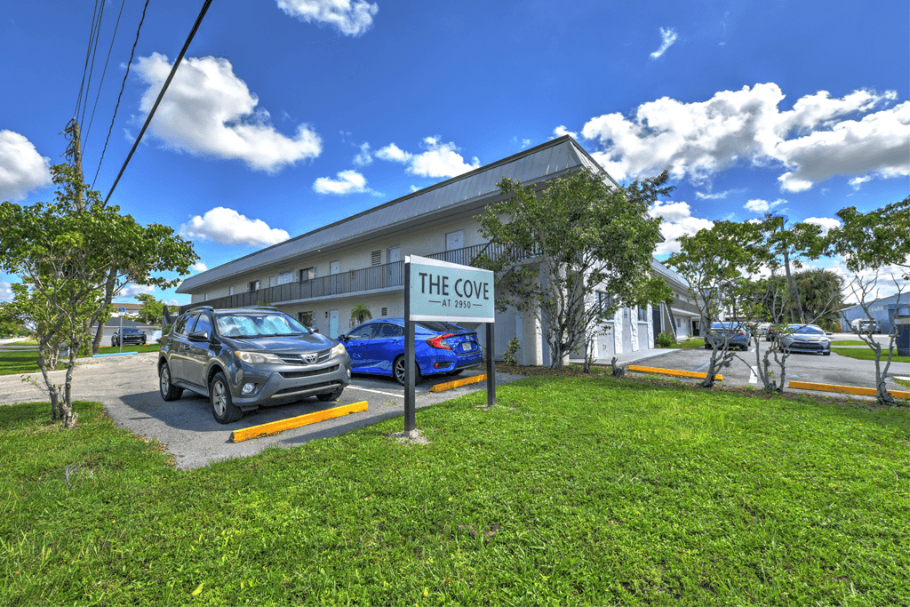 The Cove is a white building with a blue car parked in front.