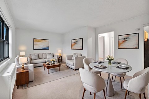 A living room with a grey couch, a coffee table, and a dining table set up.