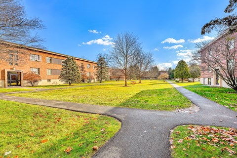 A pathway leads through a grassy area in front of a brick building.