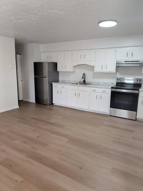 A kitchen with white cabinets and a wooden floor.