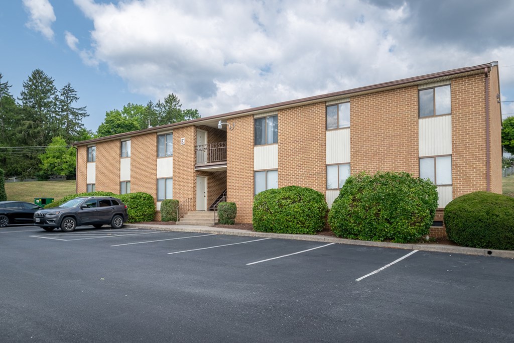 A parking lot in front of a brick apartment building.