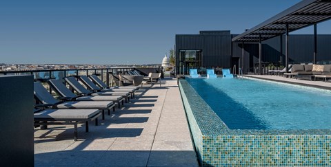 A pool with sun loungers and a building in the background.