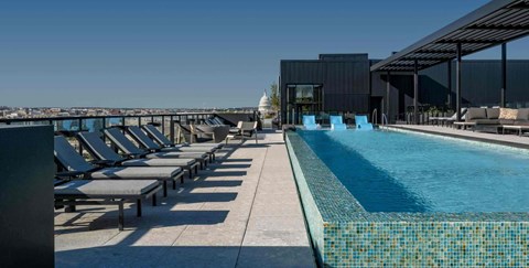 A pool area with sun loungers and a building in the background.