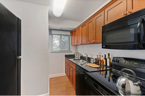 A kitchen with black appliances and wooden cabinets.
