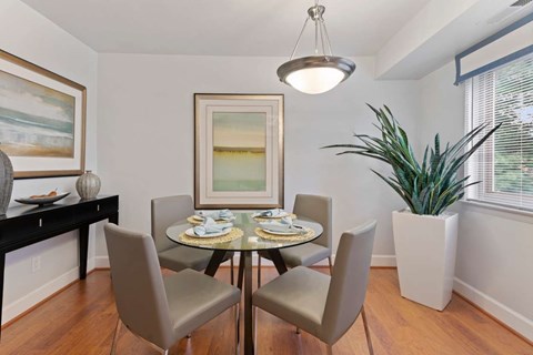 A dining room with a table set for two and a potted plant.